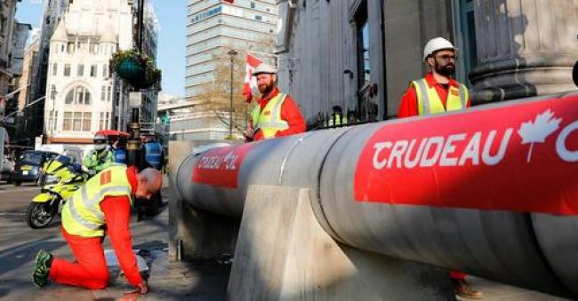 Climate activists use a mock oil pipeline to block the entrance to the Canadian Embassy on April 18, 2018 to protest the Trans Mountain Pipeline expansion. (Photo: Tolga Akmen/AFP via Getty Images)