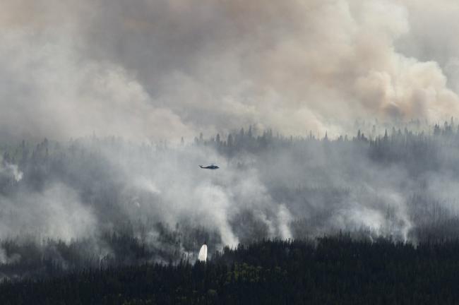 A helicopter drops a bucket of water on the Chuckegg Creek wildfire west of High Level, Alta., on May 25, 2019. Photo by Chris Schwarz, Government of Alberta / Flickr (CC BY-NC-ND 2.0)