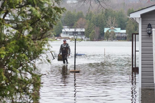 A man walks between flooded houses in Constance Bay northwest of Ottawa on April 26, 2019. Photo by Kamara Morozuk