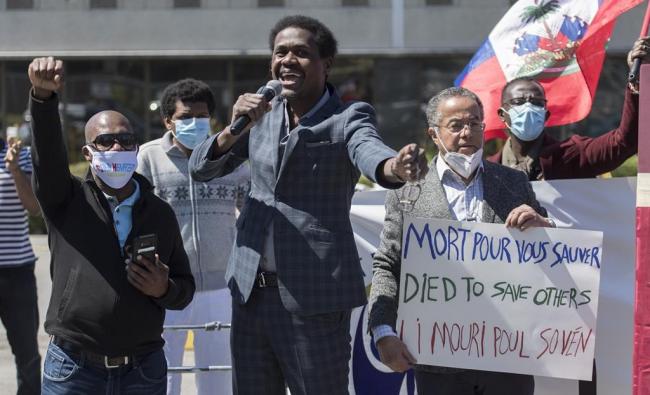 Wilner Cayo, centre, and Frantz Andre attend a demonstration outside Prime Minister Justin Trudeau's constituency office in Montreal, Saturday, May 23, 2020. THE CANADIAN PRESS/Graham Hughes