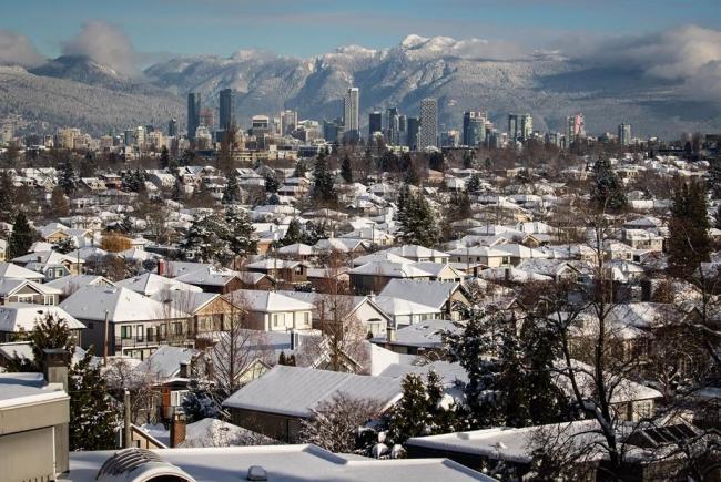 Snow-covered houses and the downtown skyline are seen with the north shore mountains in the distance in Vancouver, on Thursday, December 30, 2021. File photo by The Canadian Press/Darryl Dyck