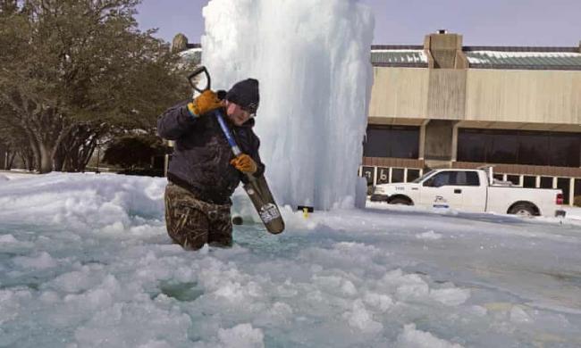 Kaleb Love, a municipal worker, breaks ice on a frozen fountain in Richardson, Texas, on Tuesday, as freezing temperatures grip the state. Photograph: LM Otero/AP