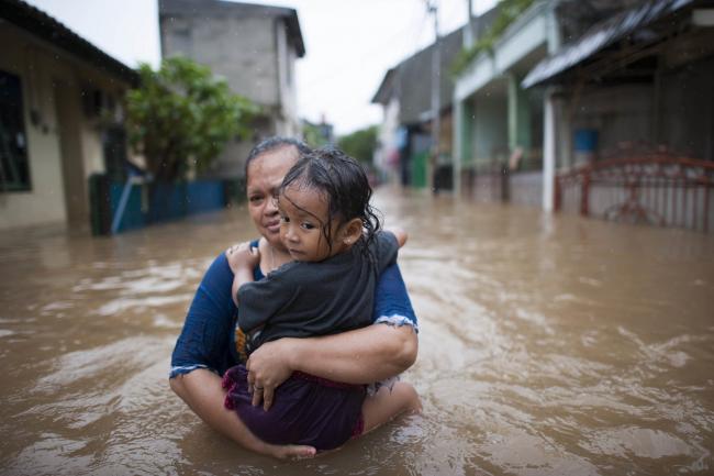 mother and child in flood - Without rich countries making the money available to poorer countries to transition to a clean economy, holding onto the Paris goal of 1.5 C will be out of reach. Photo by World Meteorological Organization(CC BY-NC-ND 2.0)