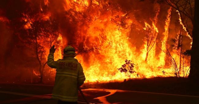 Fire and Rescue personnel run to move their truck as a bushfire burns next to a major road and homes on the outskirts of the town of Bilpin on December 19, 2019 in Sydney, Australia. (Photo: David Gray/Getty Images)