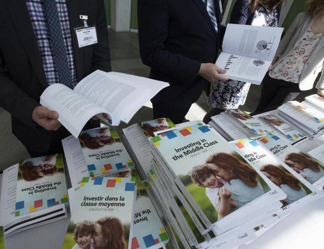 People sift through the 2019 budget booklet at a lockup session with experts and reporters in Ottawa on March 19, 2019. File photo by The Canadian Press/Fred Chartrand