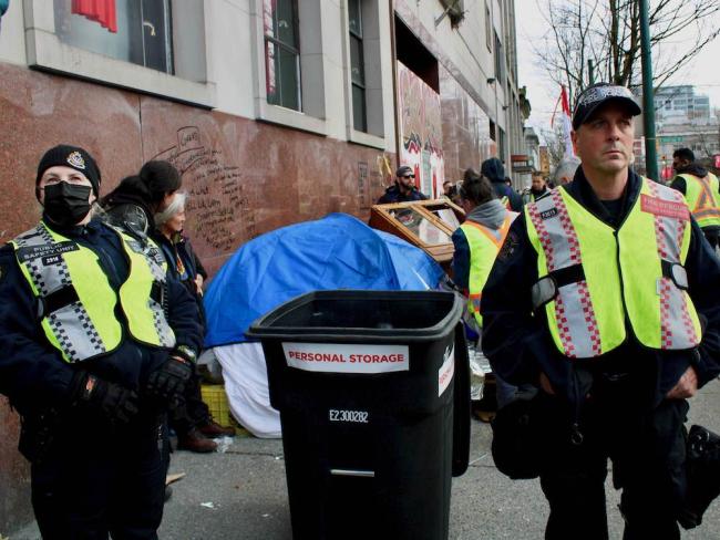 Police and city workers attempt to remove a woman’s tent from Main Street on April 5 during a camp-clearing operation that focused on East Hastings Street. Photo for The Tyee by Jen St. Denis.