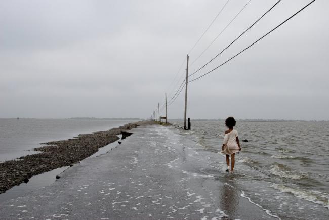 A young girl takes the road to Isle de Jean Charles, which is disappearing into the Gulf of Mexico from erosion fuelled by climate change and land subsidence accelerated by the fossil fuel industry. Photo by Stacy Kranitz / Climate Visuals Countdown