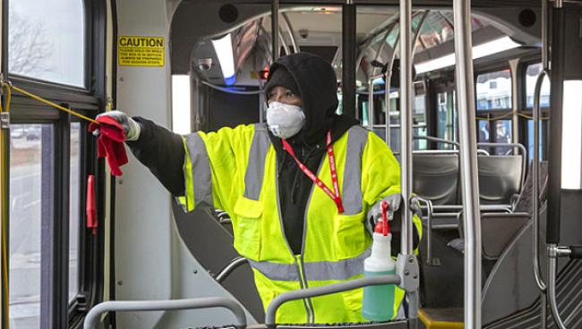 A city worker is cleaning a bus at the end of the line. Photo: Jim West / jimwestphoto.com.