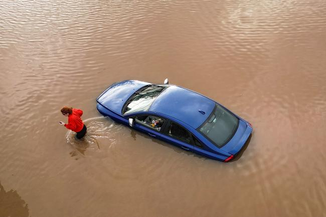 A woman checks on a flooded car in car park in Worcester, England in January, 2024. (Credit: Christopher Furlong via Getty Images.)