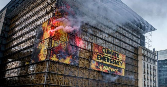 Greenpeace activists on Thursday wrap the E.U. summit venue in Brussels with images of giant flames, setting off clouds of smoke, flares and sounding a fire alarm to urge European government leaders to take immediate action to respond to the climate emergency. (Photo: Eric De Mildt/Greenpeace)