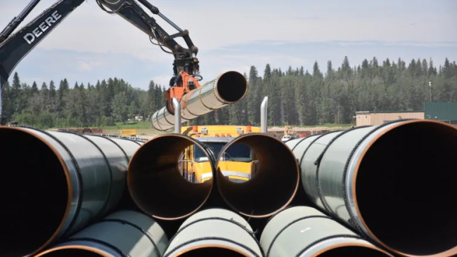 A truck loaded with pipe is unloaded at the Trans Mountain yard in Edson, Alta. (Terry Reith/CBC)