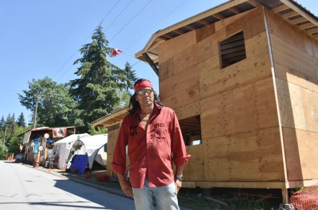 Johnny Lee stands in front of a carver's cabin he is building at Camp Cloud. Photograph By KELVIN GAWLEY