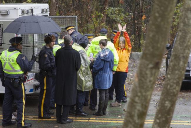 SFU molecular biology department chair Lynne Quarmby waving to supporters in handcuffs during her arrest on Burnaby Mountain on Friday. 