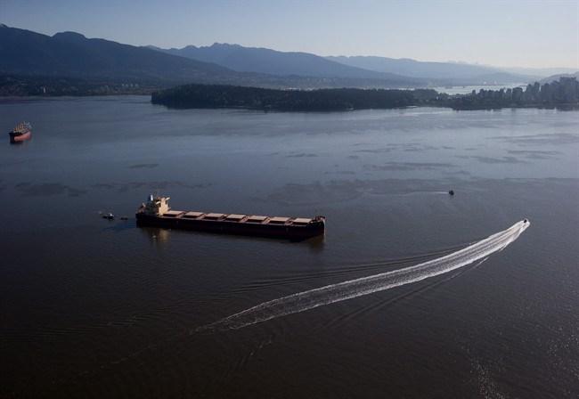 Crews on spill response boats work around the bulk carrier cargo ship Marathassa after a bunker fuel spill on Burrard Inlet in Vancouver, B.C., on Thursday April 9, 2015. The federal coast guard is defending its response to an oil spill in Vancouver's harbour amid questions about how the slick washed up on beaches to the north. THE CANADIAN PRESS/Darryl Dyck