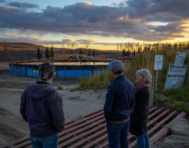 Hans Kirschbaum (left), reporter Ben Parfitt and Anja Hutgens look at a pool filled with fracking wastewater at the top of the hill above the ranchers' property. The couple is worried encroaching natural gas operations will contaminate their water source. Photo: Matt Miles / The Narwhal