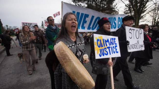 Patricia Kelly, left, of the Sto:lo First Nation, marches with Grand Chief Stewart Phillip, right, president of the Union of B.C. Indian Chiefs, to a protest outside National Energy Board hearings on the proposed Trans Mountain pipeline expansion in Burnaby, B.C., on Jan. 19, 2016. (DARRYL DYCK/THE CANADIAN PRESS)