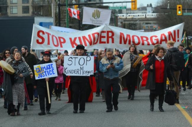 Union of B.C. Indian Chiefs Grand Chief Stewart Phillip, at centre holding sign, is joined by dozens of people rallying against the Trans Mountain pipeline expansion project and National Energy Board hearings taking place in Burnaby at the Delta Burnaby Hotel and Conference Centre.   Photograph By Cornelia Naylor 