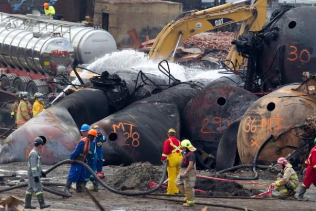 Firemen use foam to hose down a railcar as cleanup crews remove one of the toppled rail cars in Lac-Mégantic on Friday July 19, 2013.  Photograph by: Allen McInnis/Montreal Gazette , Postmedia News
