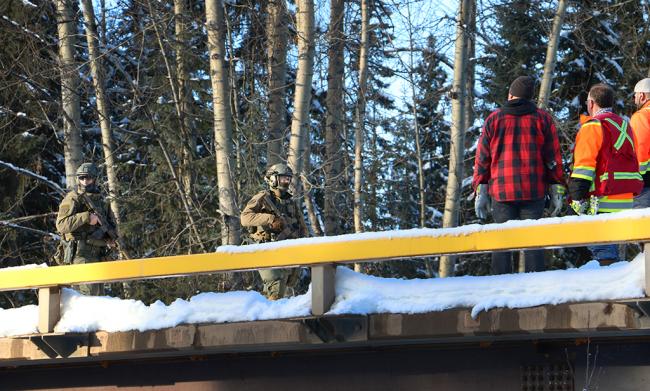 RCMP tactical officers stand on a bridge on the Morice Forest Service Road while arrests were underway on Nov. 18, 2021. BC’s Public Safety Ministry approved the use of provincial resources despite flooding underway in the province’s southwest. Photo by Amanda Follett Hosgood.