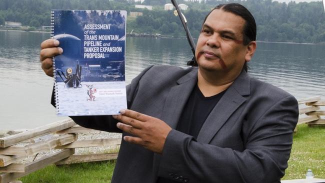 Rueben George holds a copy of Tsleil-Waututh's assessment of the Trans Mountain Pipeline project. Photo: Carlos Tello