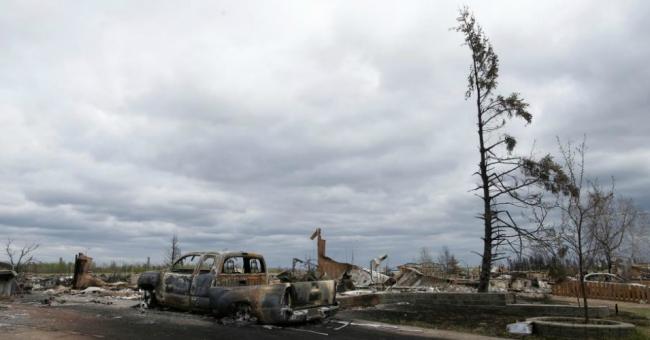 A charred vehicle and homes are pictured in the Beacon Hill neighbourhood of Fort McMurray, Alberta, Canada, May 9, 2016 after wildfires forced the evacuation of the town. (Photo: Chris Wattie/Reuters)
