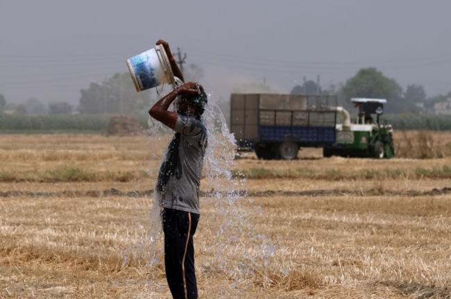 A farmer pours water on himself during a recent heat wave in the Ludhiana district of Punjab, India. Photographer: T. Narayan/Bloomberg
