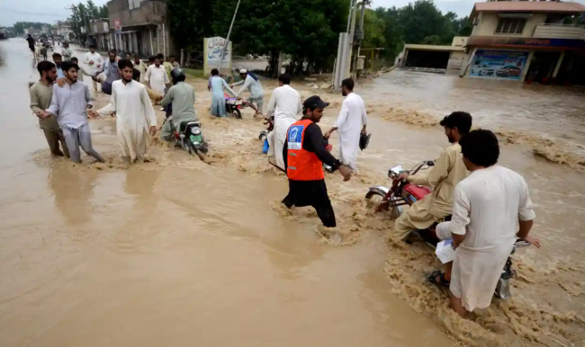 Displaced people wade through a flooded area in Peshawar, Pakistan. The country’s flooded southern Sindh province braced on Sunday for a fresh deluge. Photograph: Anadolu Agency/Getty Images