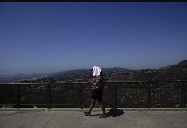 Tekosha Seals, a tourist visiting from Georgia, walks with a tower over her head at the Griffith Observatory in Los Angeles, Sept. 6, 2022, during a heat wave. (AP Photo/Jae C. Hong, File)