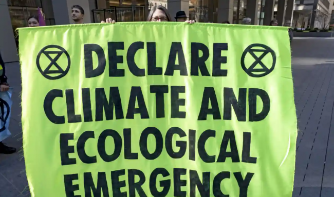 A climate activist holds banner in front of the NYC office of JPMorgan Chase bank's new headquarters during an ‘Occupy Park Avenue’ protest on 29 October 2022 in New York City. Photograph: Ron Adar/Rex/Shutterstock