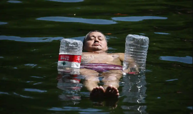 A man uses water bottles for flotation as he cools off in a canal in Beijing amid the heatwave while swathes of northern China sweltered in 40-degree temperatures. Photograph: Greg Baker/AFP/Getty Images