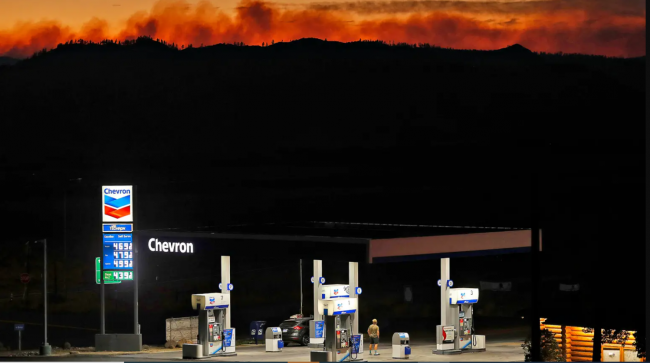 A 2021 wildfire lights up the ridge behind a gas station in Lassen County, California. Scott Strazzante / The San Francisco Chronicle via Getty Images