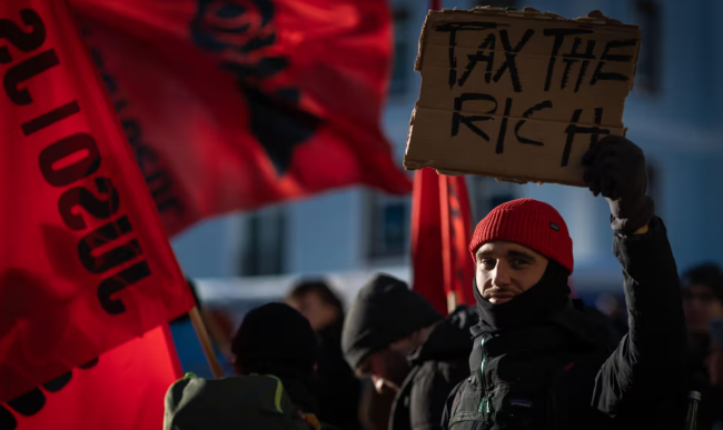 A protester holds a placard during a rally against the 54th World Economic Forum in Davos, Switzerland, 14 January 2024. Photograph: Andy Barton/Alamy