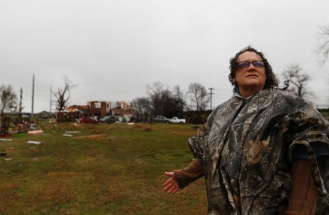 Evelyn Lindstrom looks for her cat that ran away as her home, seen behind her, was damaged by Saturday night's tornado in Copeville, Texas. Tornadoes that swept through the Dallas area caused substantial damage and at least 11 people died either from the storm or related traffic accidents. (Rachel Woolf/The Dallas Morning News via AP) MANDATORY CREDIT (Rachel Woolf/The Dallas Morning News/Associated Press)