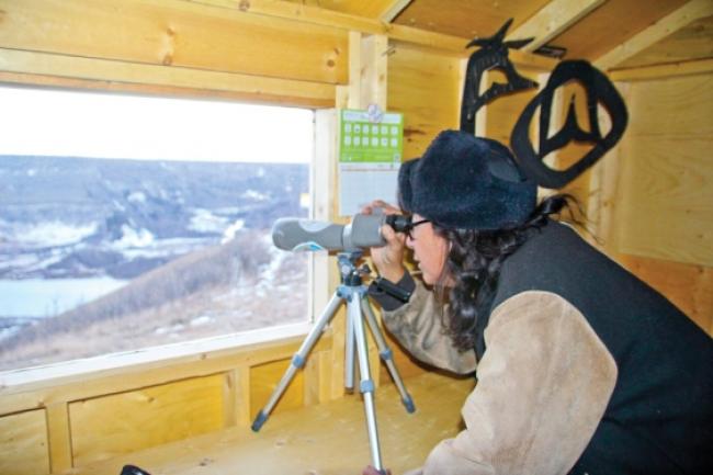 George Desjarlais looks through a telescope at the Site C dam construction from an observation shack built by the Treaty 8 Tribal Association overlooking the Peace River.   Photo By William Stodalka - See more at: http://www.alaskahighwaynews.ca/regional-news/site-c/site-c-opponents-keeping-an-eye-on-dam-s-construction-from-new-observation-shack-1.2111836#sthash.BdkmakXe.3OEmiFp9.dpuf