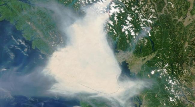 NASA’s Terra satellite acquired this images in the late morning on July 5, 2015. The tan and gray smoke almost completely obscures the Strait of Georgia and southern Vancouver Island. Winds shifted abruptly between July 5 and 6, driving the smoke plume toward the east, dispersing it in some places while fouling the air in areas to the east, such as the Fraser Valley.