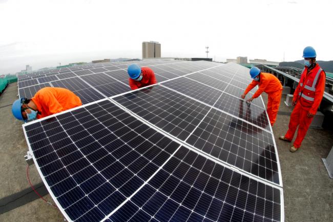 Workers install photovoltaic panels on the roof of a fish processing plant on Nov. 16, 2021 in Zhoushan, Zhejiang Province of China. Credit: Yao Feng/VCG via Getty Images