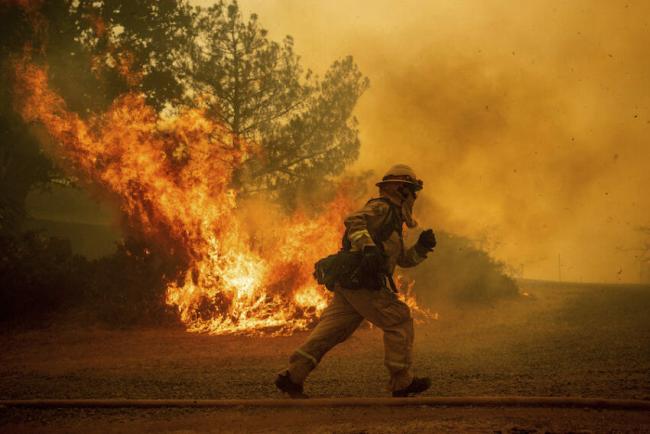 A firefighter races to save a home in Lakeport, Calif. The residence eventually burned. (Noah Berger / AP)