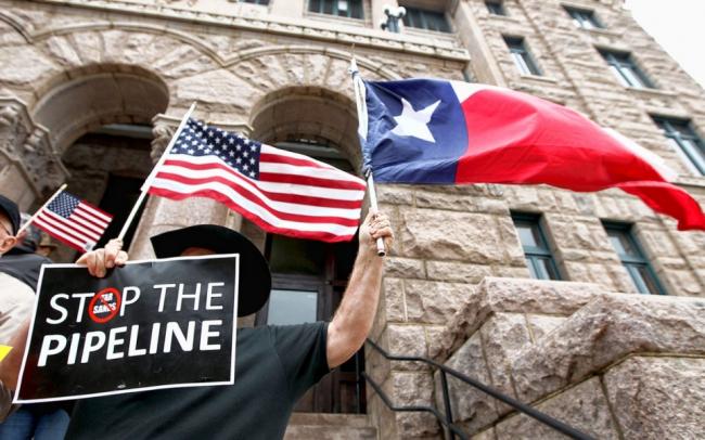 Texan Eddy Radillo holds a Texas flag and a sign opposing the Keystone XL pipeline during a rally in Paris, Texas in 2012.Sam Craft/The Paris News, via AP