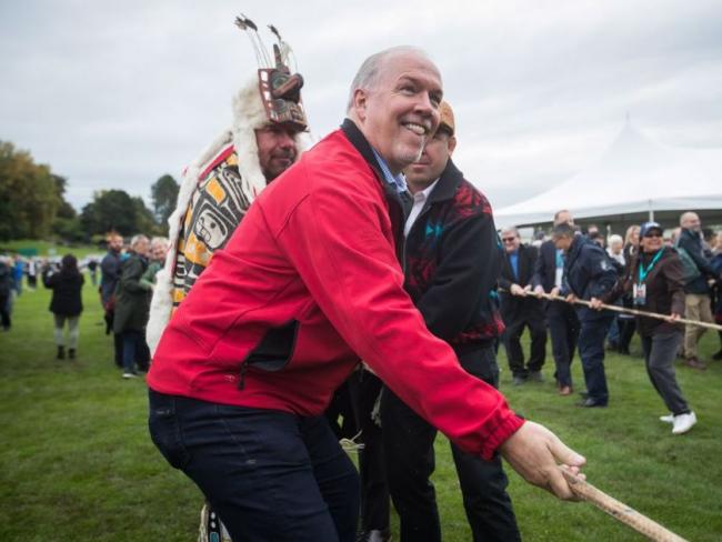 B.C. Premier John Horgan, front, and Hereditary Chief David Mungo Knox, back left, of the Kwakiutl First Nation, help raise a replica of a Haida totem pole on the traditional territory of the Semiahmoo First Nation, at the Douglas-Peace Arch border crossing, in Surrey, B.C., on Friday September 21, 2018. DARRYL DYCK / THE CANADIAN PRESS