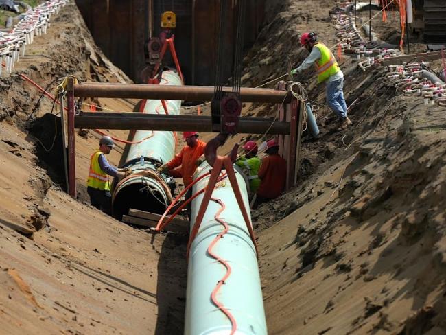 The plan to daily pump 1.4 million more barrels of bitumen includes expanding the Trans Mountain pipeline, shown here being buried in Abbotsford, BC, in 2023. Photo by Darryl Dyck, the Canadian Press.