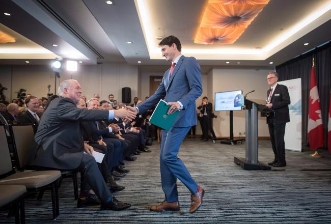 Prime Minister Justin Trudeau and B.C. Premier John Horgan shake hands as LNG Canada CEO Andy Calitz, back right, watches during a news conference in October 2018. Photo by Darryl Dyck, the Canadian Press