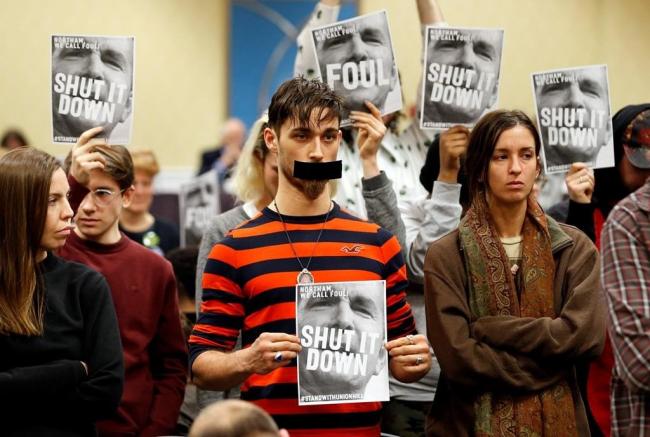 Protesters hold signs as they turn their backs on a meeting of the Virginia State Air Quality Control Board in Richmond, Va., on Tuesday, Jan. 8, 2019. Photo by The Associated Press/Steve Helber