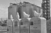 A memorial to schoolchildren killed in the Great East Japan Earthquake of 2011 stands next to silos used to store wood pellets at a new thermal electricity plant in Sendai. Photo submitted.