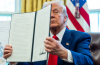 President Trump held up an executive order at a signing ceremony in the Oval Office this month.Credit...Eric Lee/The New York Times
