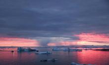 The sun sets as rain falls beyond floating ice and icebergs in Disko Bay, Greenland. Photograph: Mario Tama/Getty Images