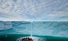 Under a blanket of clouds, tourists watch a meltwater waterfall on an icecap. Photograph: Ralph Lee Hopkins/National Geographic Society/Corbis