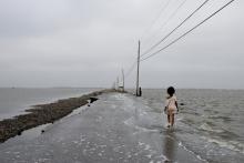 A young girl takes the road to Isle de Jean Charles, which is disappearing into the Gulf of Mexico from erosion fuelled by climate change and land subsidence accelerated by the fossil fuel industry. Photo by Stacy Kranitz / Climate Visuals Countdown