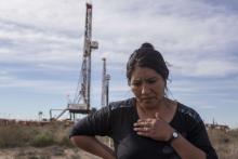 Mabel Izaza, a member of the Indigenous Mapuche ethnic group demanding environmental damage from oil companies, stands in front of a fracking rig at Vaca Muerta on September 15, 2014, in Añelo, Argentina. RICARDO CEPPI / GETTY IMAGES