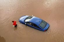 A woman checks on a flooded car in car park in Worcester, England in January, 2024. (Credit: Christopher Furlong via Getty Images.)