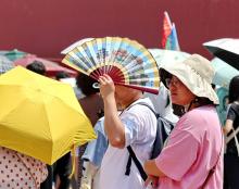Tourists shield themselves from the sun while visiting the Palace Museum during a heat wave on July 6 in Beijing, China. Credit: VCG via Getty Images